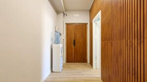 A hallway with wooden paneling on one side, a water dispenser, and a door at the end.