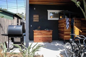 Ein moderner Außenbereich mit Küchenzeile, Grill, Holzschränken und einem Fahrrad.