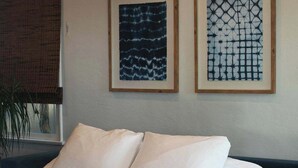A bed with white bedding and a grey throw blanket, a dark blue sofa, and two framed abstract artworks on the wall. - Industrial-Inspired 2-Story California Beach House (Oceanside)