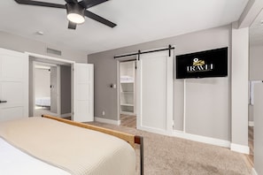 A bedroom with a bed, a wardrobe, a sliding door closet, a ceiling fan, and a sign on the wall.