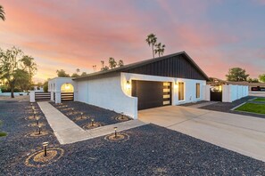 A modern building with a garage, a driveway, and a landscaped area with decorative lights.