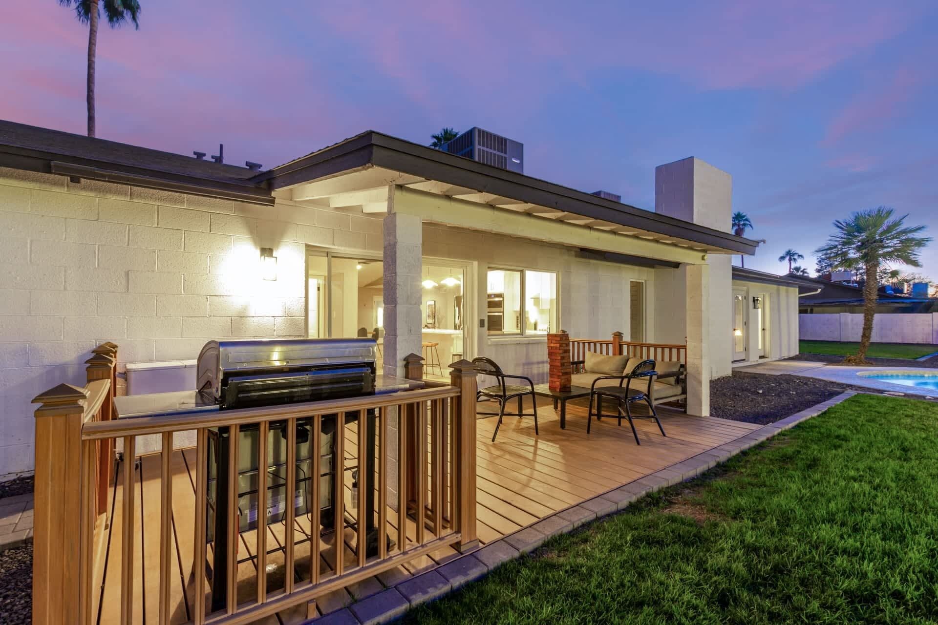 Une terrasse avec un barbecue, des sièges d’extérieur et une piscine.