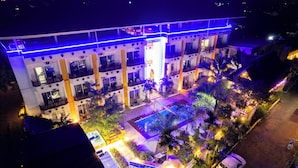 Un hôtel à plusieurs étages, doté de balcons, d’une piscine et d’une enseigne indiquant « Canary Hotel ».