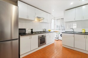 A modern kitchen with white cabinets, stainless steel appliances, and a tiled backsplash.
