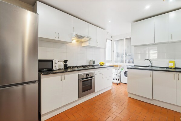 A modern kitchen with white cabinets, stainless steel appliances, and a tiled backsplash. - Private terrace overlooking Sagrada Familla in a quiet area (Barcelona)