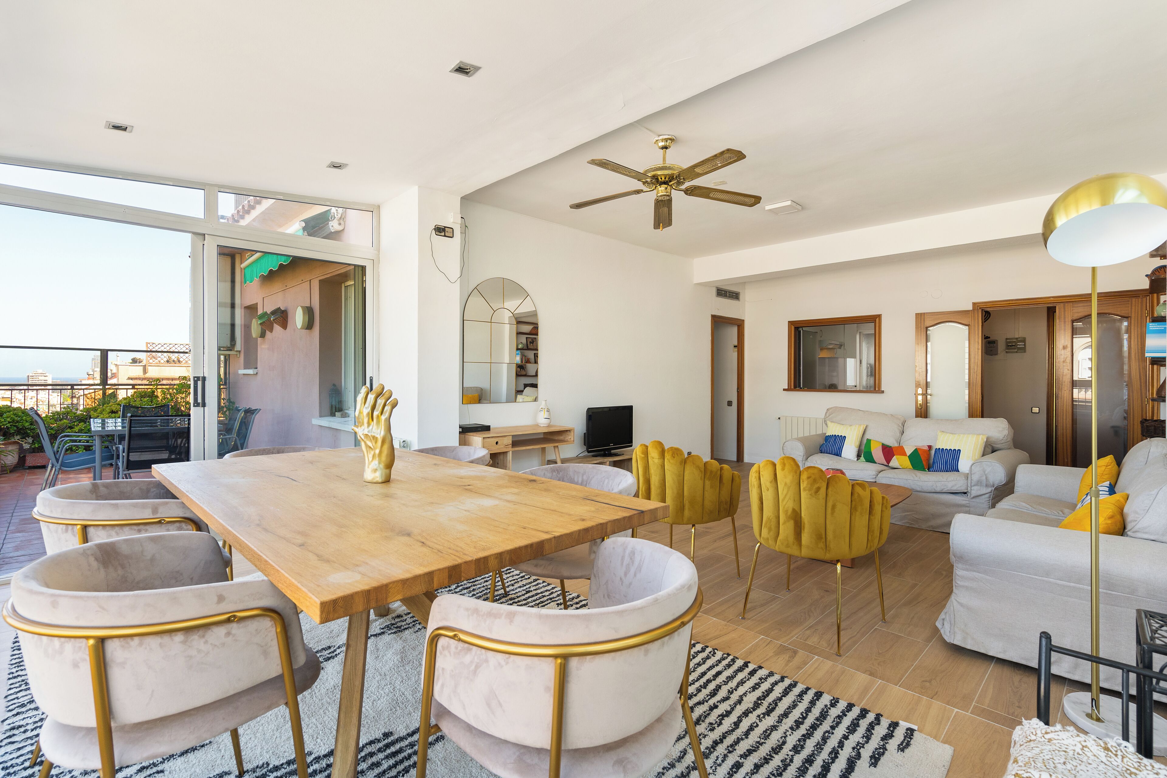 Amplia sala de estar con una mesa de comedor de madera, asientos cómodos y un ventilador de techo.