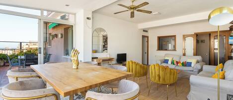 Amplia sala de estar con una mesa de comedor de madera, asientos cómodos y un ventilador de techo.