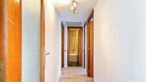 A hallway with wooden doors, a tiled floor, and a ceiling light fixture.