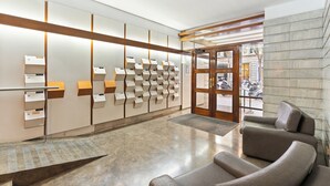 A modern lobby with a reception desk, seating area, and a wall-mounted information display.