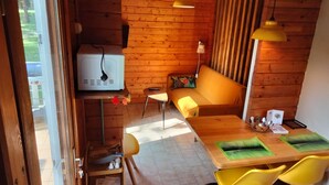 Ein gemütliches Blockhauss-Interieur mit Holzausstattung, einer Couch, einem Esstisch mit Stühlen und einem Fernseher.