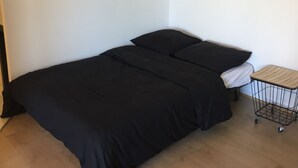 Une pièce comprenant un lit, une petite table d’appoint en bois et un élément décoratif mural.