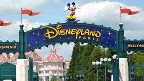 L’entrée de Disneyland Paris, avec Mickey Mouse au sommet, un panneau orné d’étoiles et un bâtiment en arrière-plan.