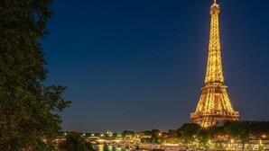 Une vue nocturne de la Tour Eiffel, avec une rivière et des routes illuminées au premier plan.