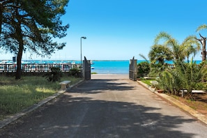 A paved pathway leading to a beach with a clear blue sky and calm sea. - 3808 Residence Garden Sea - Trilo 3 by Barbarhouse (Porto Cesareo)