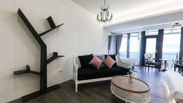 A modern living room with a black sofa, a round coffee table, and a chandelier.