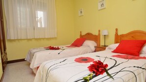A hotel room with two beds, each with a wooden headboard and red pillows.