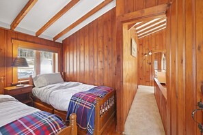 Une chambre dans une cabane en bois, avec un lit, une table de chevet, une lampe et une fenêtre.