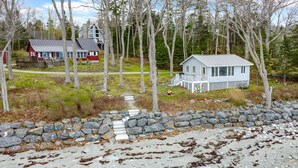 A coastal property with a stone wall, a small dock, and two houses. - Tide's Edge-New Oceanfront! (Surry)