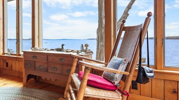 A wooden cabin with a desk, chair, and large windows overlooking a body of water. - Tide's Edge-New Oceanfront! (Surry)