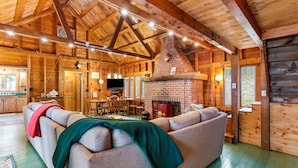 A log cabin interior with a fireplace, wooden furniture, and a dining area. - Seaside! New-Oceanfront! (Surry)