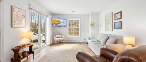 A modern living room with a sofa, a brown leather chair, a coffee table, and a TV.