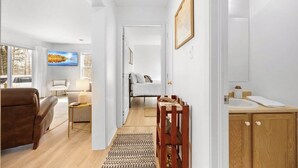 Ein modernes Hotelzimmer mit Sofa, Fernseher, Bett, Holzschrank und Blick ins Freie.
