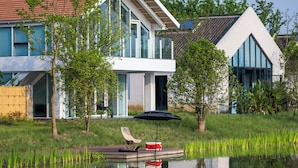 A modern house with a dock extending into a calm pond, surrounded by lush greenery and a clear sky. - Jiangnan House  Yangcheng Lake (Suzhou)