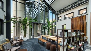 A modern interior with a high ceiling, large windows, and a central seating area with tables and chairs. - Jiangnan House  Yangcheng Lake (Suzhou)