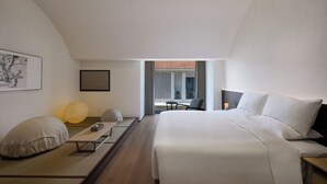 A modern hotel room with a large bed, a small table, and a chair. There is a window with a view of the outside. - Jiangnan House  Yangcheng Lake (Suzhou)