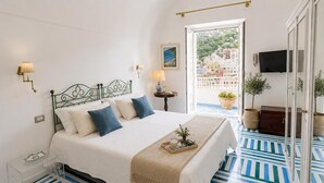 A bedroom with a bed, bedside lamps, a view of buildings, a TV, and a potted plant. - Villa Positano with sea view (Positano)
