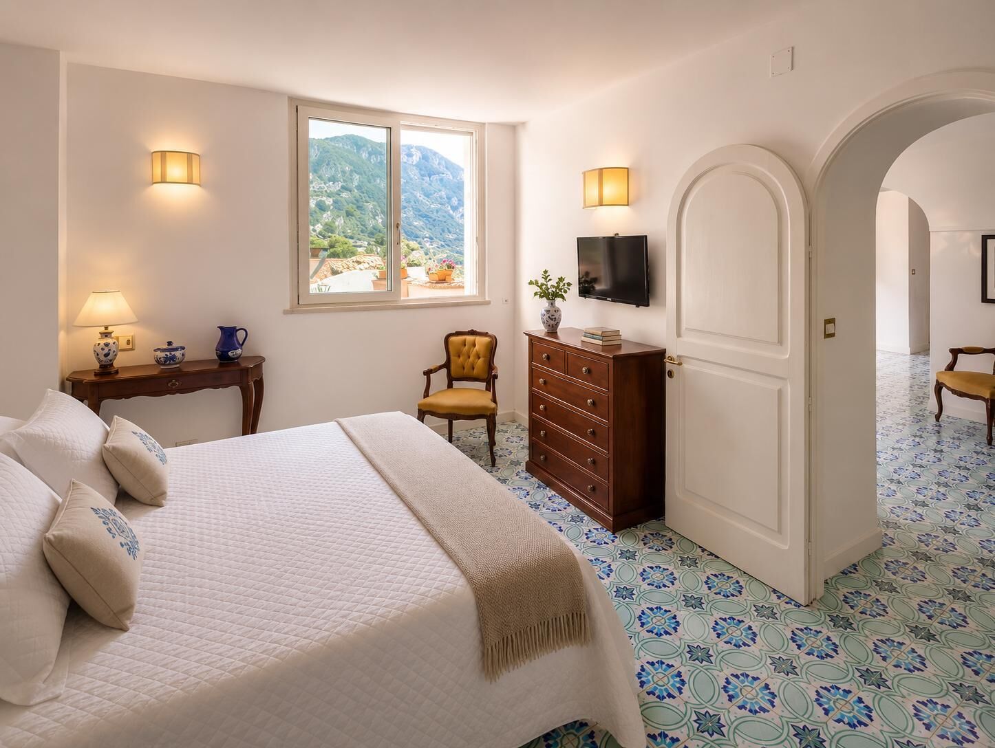 Une chambre à coucher comprenant un lit, une commode, une chaise, un téléviseur et une fenêtre donnant sur la montagne.
