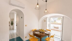 A dining area with a round table, yellow chairs, and a view of a balcony. - Villa Positano with sea view (Positano)