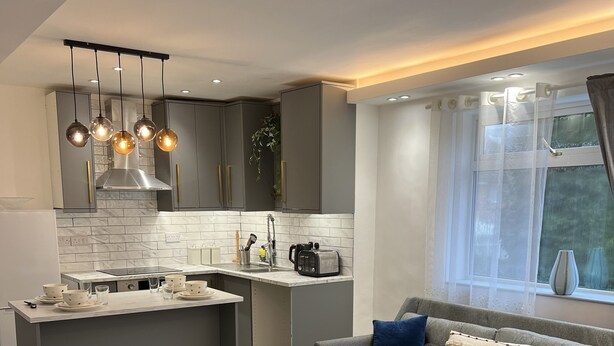 A modern kitchen with grey cabinets, a central island, and pendant lighting. - Luxury 2 Bed Apartment in Royal Sutton Coldfield (Sutton Coldfield)