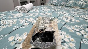 A neatly made bed with a floral bedspread, a tray with glasses and chocolates, a lamp, and a wardrobe in the background. - Luxury 2 Bed Apartment in Royal Sutton Coldfield (Sutton Coldfield)