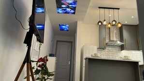 A modern kitchen with a central island, a ceiling-mounted projector, and a potted plant. - Luxury 2 Bed Apartment in Royal Sutton Coldfield (Sutton Coldfield)