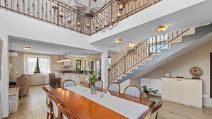 A spacious dining area with a long wooden table, surrounded by chairs, and a staircase leading to an upper level. - Luxury and Stylish Villa Campagna with sauna, private pool and beautiful garden (Pula)