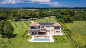 A large house with a swimming pool, surrounded by lush greenery and a clear sky. - Luxury and Stylish Villa Campagna with sauna, private pool and beautiful garden (Pula)