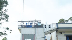 A building with a sign that reads "GALAXY HOTEL" and a visible window with a person inside. - Royal Galaxy Inn By Elgozo (Yercaud)