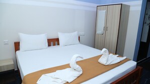 A hotel room with a bed, a wooden wardrobe, and a mirror. - Royal Galaxy Inn By Elgozo (Yercaud)