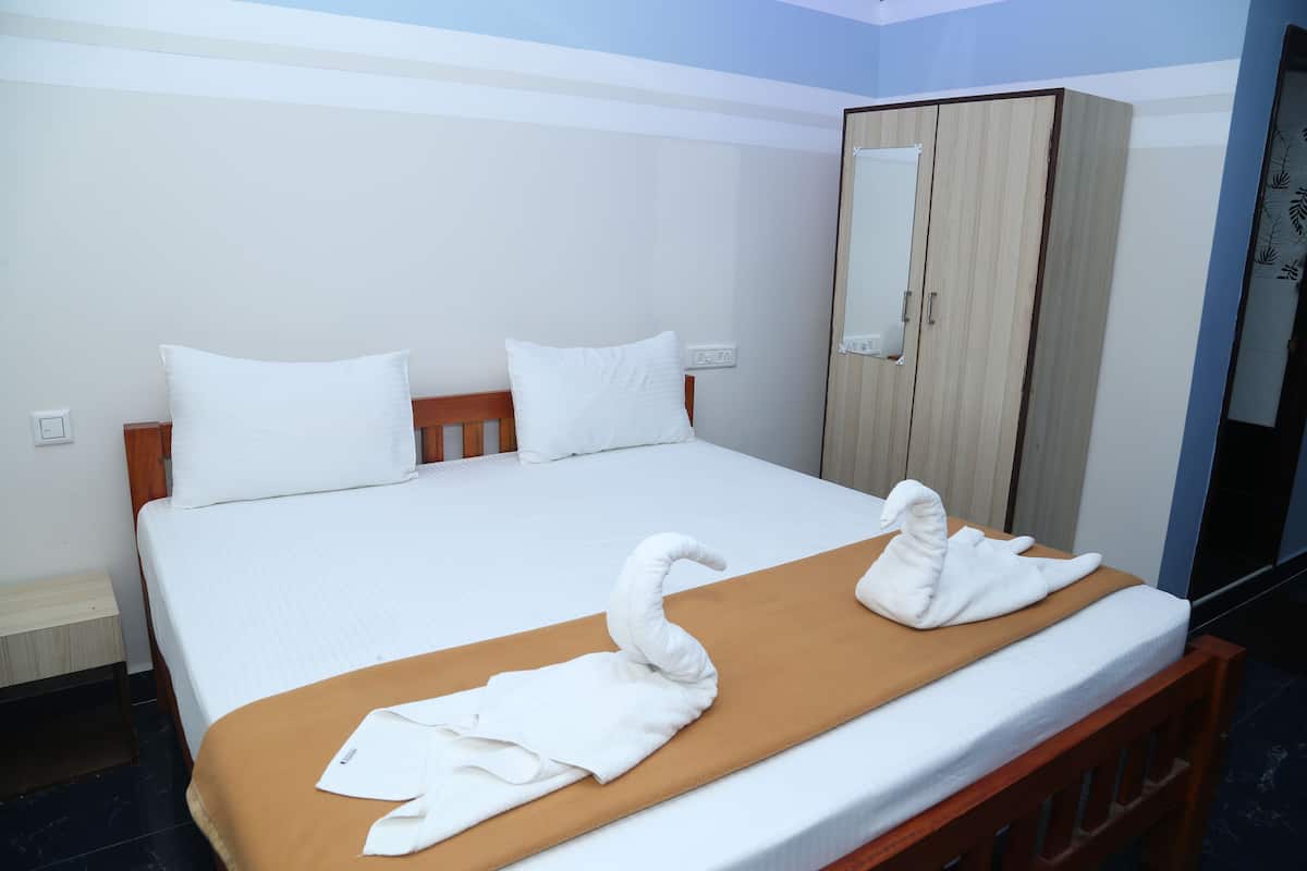 A hotel room with a bed, a wooden wardrobe, and a mirror.