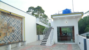 A modern building with a tiled wall, a staircase, and a small office area. - Royal Galaxy Inn By Elgozo (Yercaud)