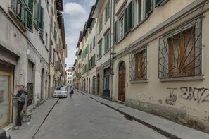 A narrow street lined with historic buildings, some with green shutters, and a graffiti-covered wall. - Central Panoramic Terrace (Florence)