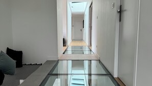 A modern interior with a glass floor leading to a hallway, white walls, and a door on the right. - Luxury villa heated pool jacuzzi sauna (Pérols)