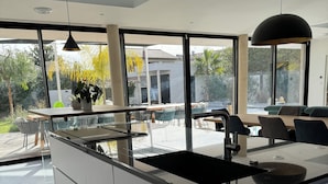 A modern kitchen with a large island, large windows, and a view of the outdoors. - Luxury villa heated pool jacuzzi sauna (Pérols)