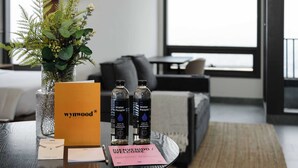 A hotel room with a round table featuring a welcome card, two water bottles, and a decorative plant in a glass vase. - w*| Bright 1BR apts w/ lovely views of Cuauhtémoc (Ciudad de México)
