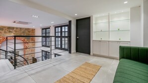 Un intérieur moderne avec un escalier, un canapé vert et un mur en pierre.