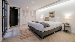 Une chambre à coucher moderne avec un grand lit, une table de chevet et une œuvre d’art accrochée au mur.