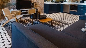 Una sala de estar moderna con una pared de piedra, un televisor de pantalla plana, un sofá y una mesa de centro.