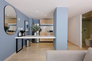 Enjoy a compact living space with a kitchenette area, featuring a breakfast bar, mirror, and potted plant.