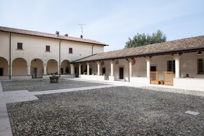 A courtyard with a building featuring arches and a tiled roof.